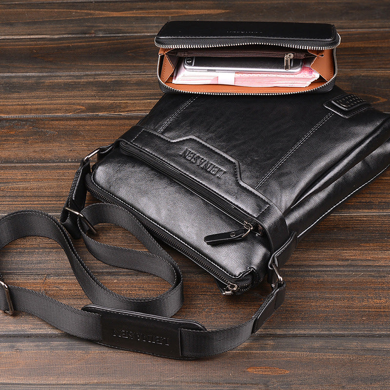 Black leather bag with a shoulder strap on a wooden surface