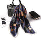 Floral scarf draped over a black handbag with a white background