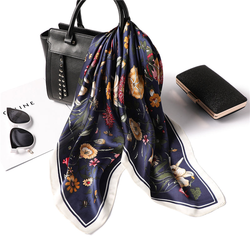Floral scarf draped over a black handbag with a white background