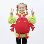 Child wearing a red crab-shaped backpack with a neutral background