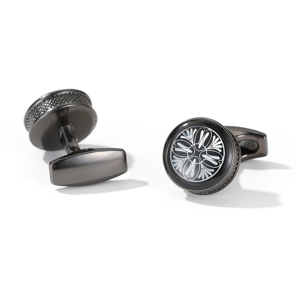 Black cufflinks with intricate design on a white background