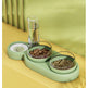 Green pet feeder with food and a glass on a yellow surface