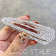 Hand holding a crystal-studded hair clip with a blurred background
