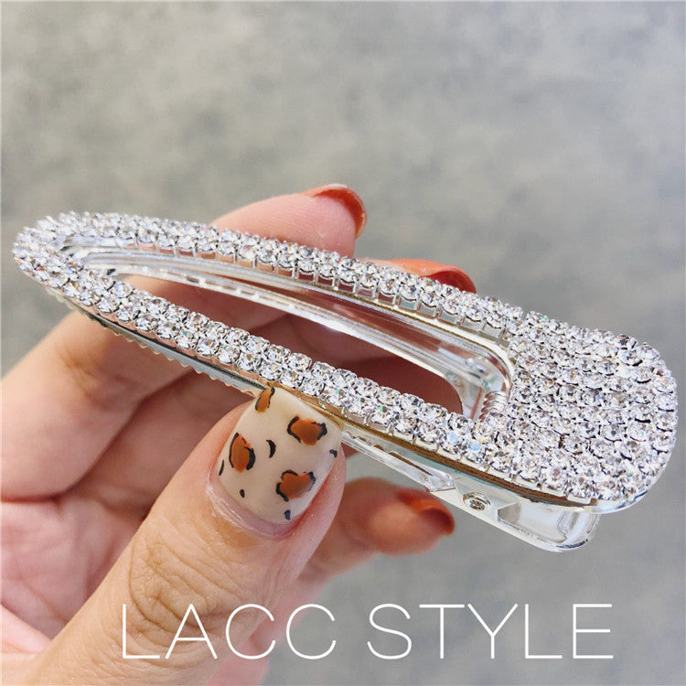 Hand holding a crystal-studded hair clip with a blurred background