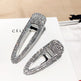 Two silver hair clips with clear gemstones on a white surface with 'Celine' branding.