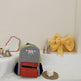 Gray and red backpack with a yellow bow on a white surface