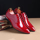 Shiny red dress shoes with gold laces on a dark background