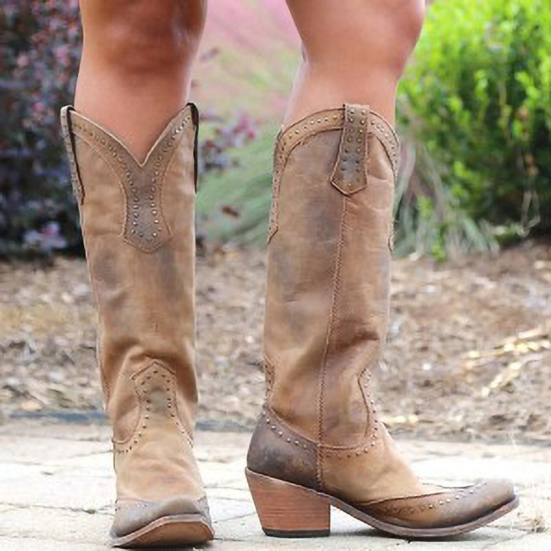 Brown cowboy boots worn by a person with a blurred natural background