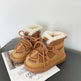 Pair of brown suede boots with white fur lining on a gray surface.