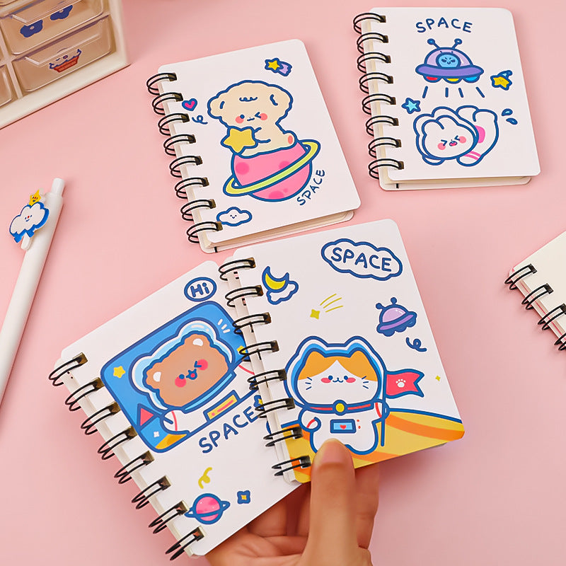 Three small spiral-bound notebooks with space-themed illustrations on a pink background