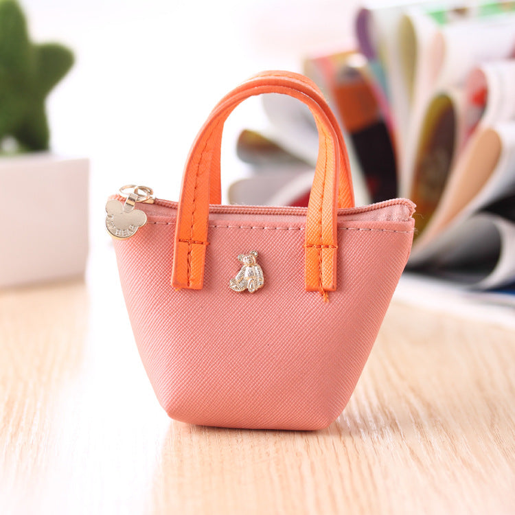 Small pink purse with orange handle on a wooden surface