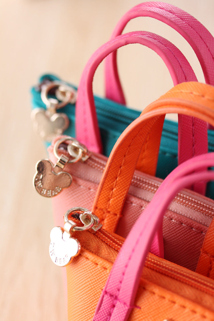 Close-up of colorful handbags with decorative charms on a beige background