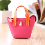 Small pink handbag with orange handle on a wooden surface