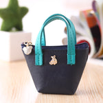Small black handbag with teal handles on a wooden surface