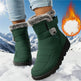 Green winter boots with fur trim worn in the snow, with a fiery graphic in the corner.