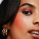 Close-up of a woman's face with gold earrings and makeup.