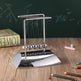 Newton's cradle on a wooden desk with books and pencils in the background
