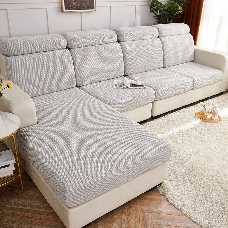 Gray and beige sectional sofa in a living room setting with a rug and side table.