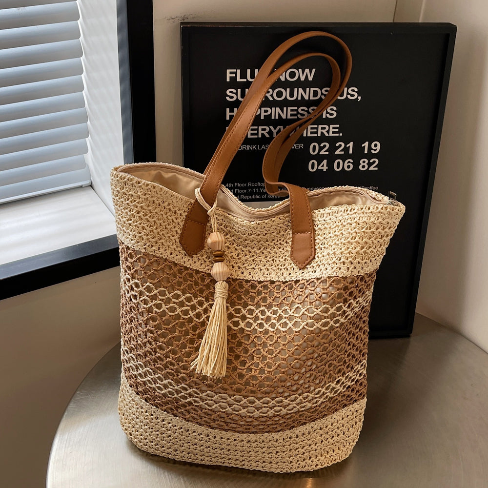Woven tote bag with a tassel on a surface near a window