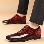 Red and black patterned dress shoes worn with dark pants on a beige background
