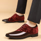 Red and black patterned dress shoes worn with dark pants on a beige background