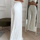 Woman wearing a white outfit with a matching skirt in front of a mirror.