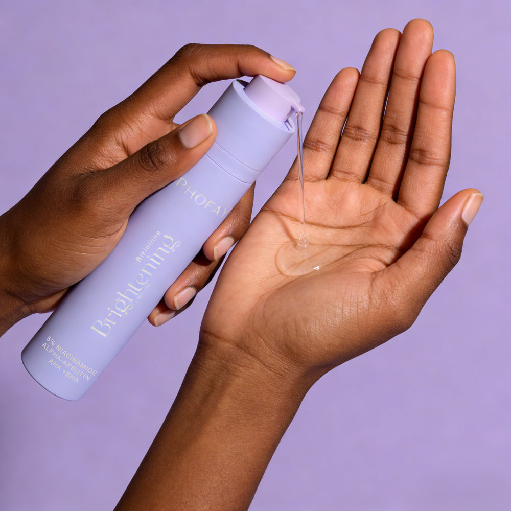 Hand holding a bottle of skincare product with a purple background