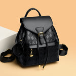 Black quilted backpack with gold accents on a beige background