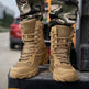 Tan tactical boots with laces worn by a person in camouflage pants, standing on a vehicle.