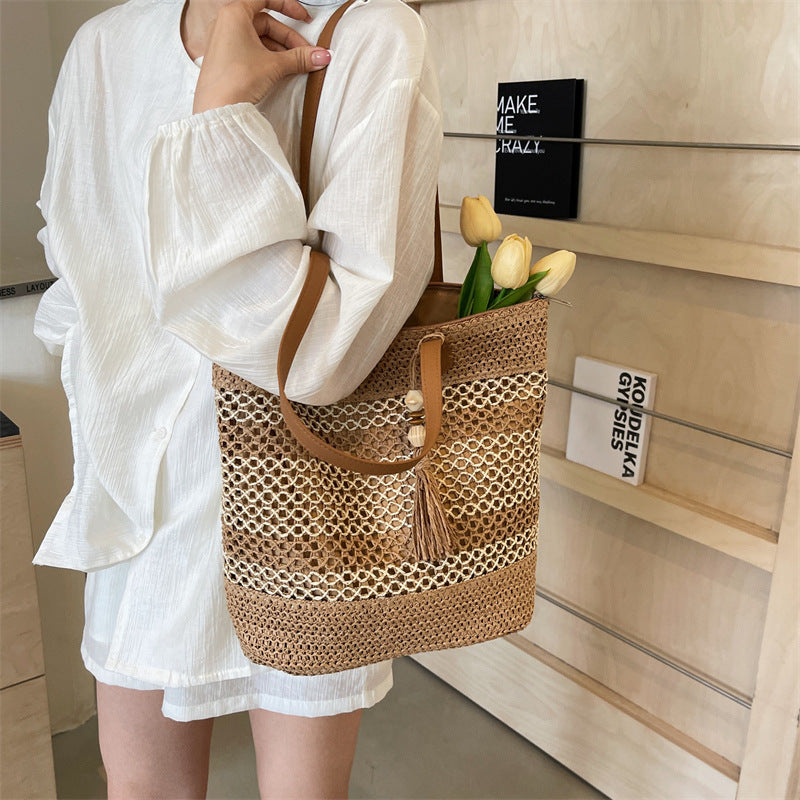 Person holding a woven handbag with tulips against a neutral background