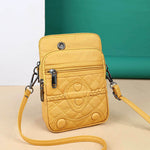 Yellow quilted crossbody bag with braided strap on a beige surface with teal background