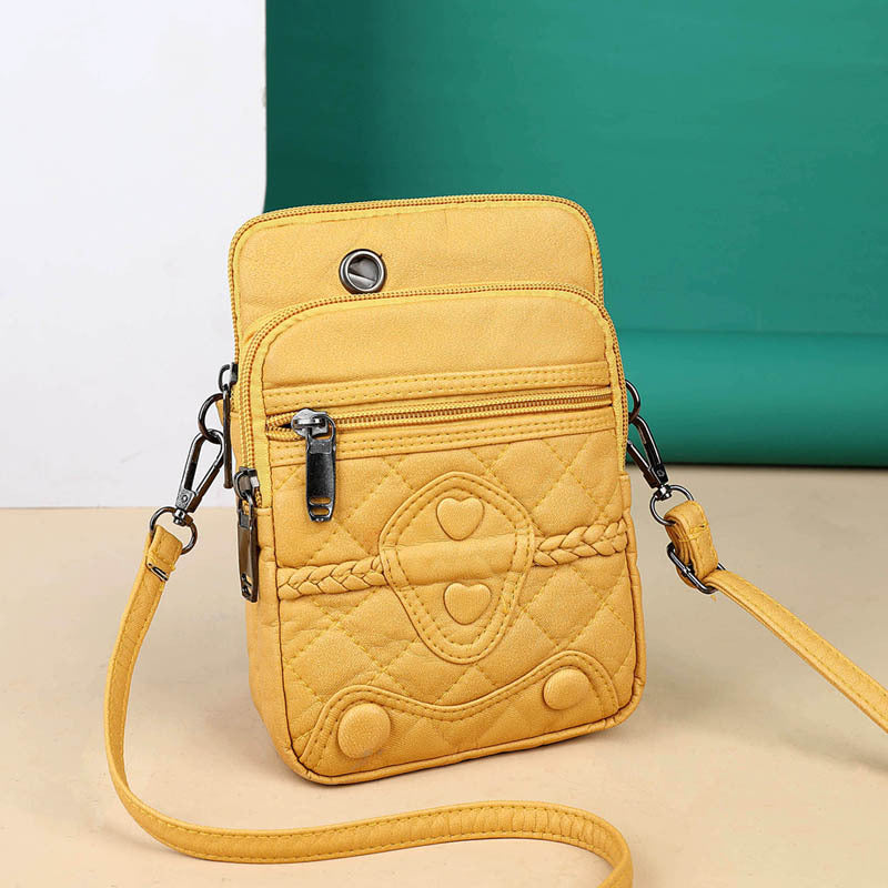 Yellow quilted crossbody bag with braided strap on a beige surface with teal background