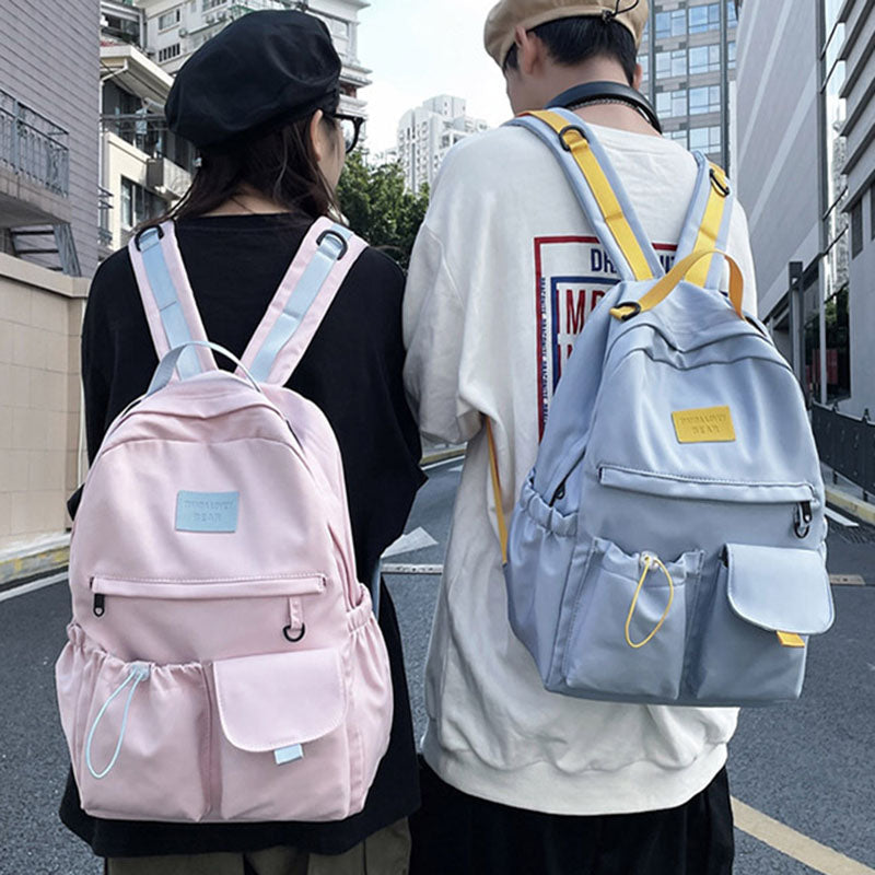 Two people wearing backpacks on a city street.
