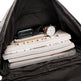 Black backpack with a stack of books, a smartphone, and a watch inside.