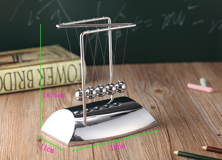Newton's cradle on a wooden surface with measurement markings