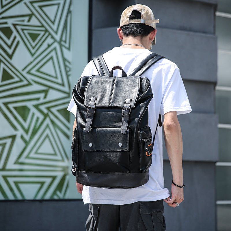 Person wearing a black backpack in front of a geometric-patterned wall.