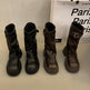 Four black and brown boots displayed on a white surface with a 'Paris' sign in the background.