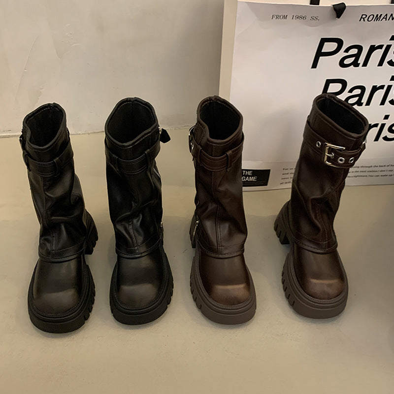 Four black and brown boots displayed on a white surface with a 'Paris' sign in the background.