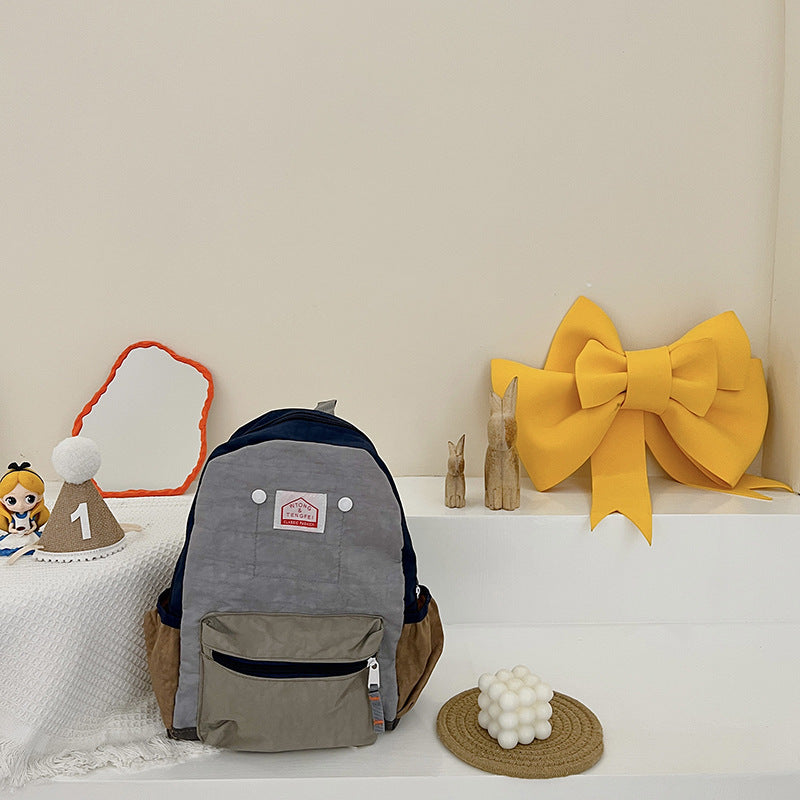 Gray backpack with a logo on a white surface with decorative items around