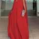 Red evening gown with a cape worn by a person indoors.