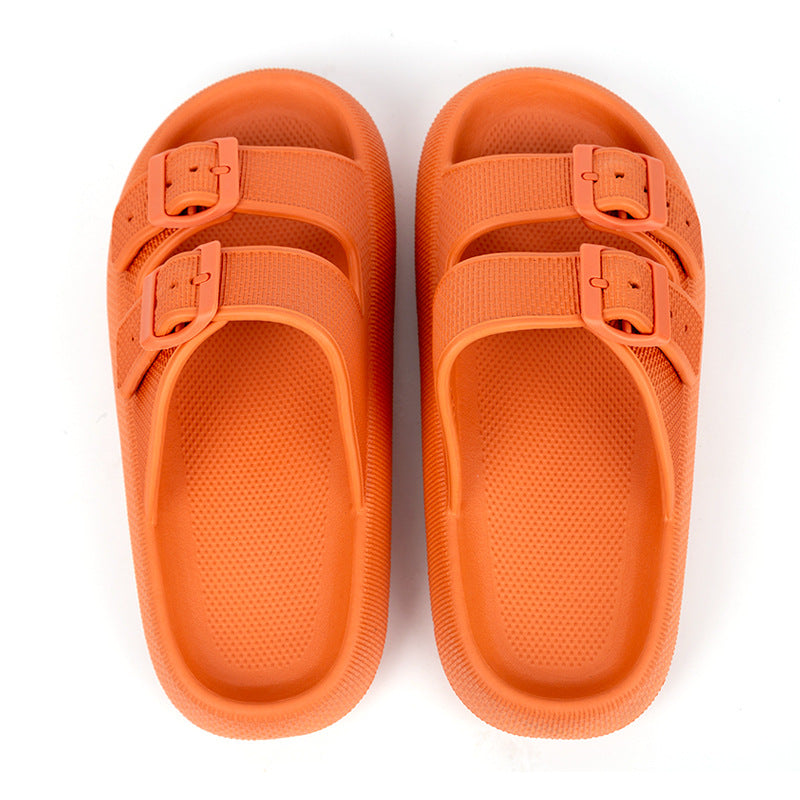 Pair of orange sandals with buckle straps on a white background
