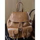 Brown leather backpack with silver buckles on a dark surface