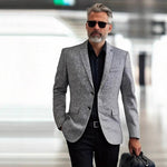 Man wearing a gray blazer and sunglasses in an indoor setting