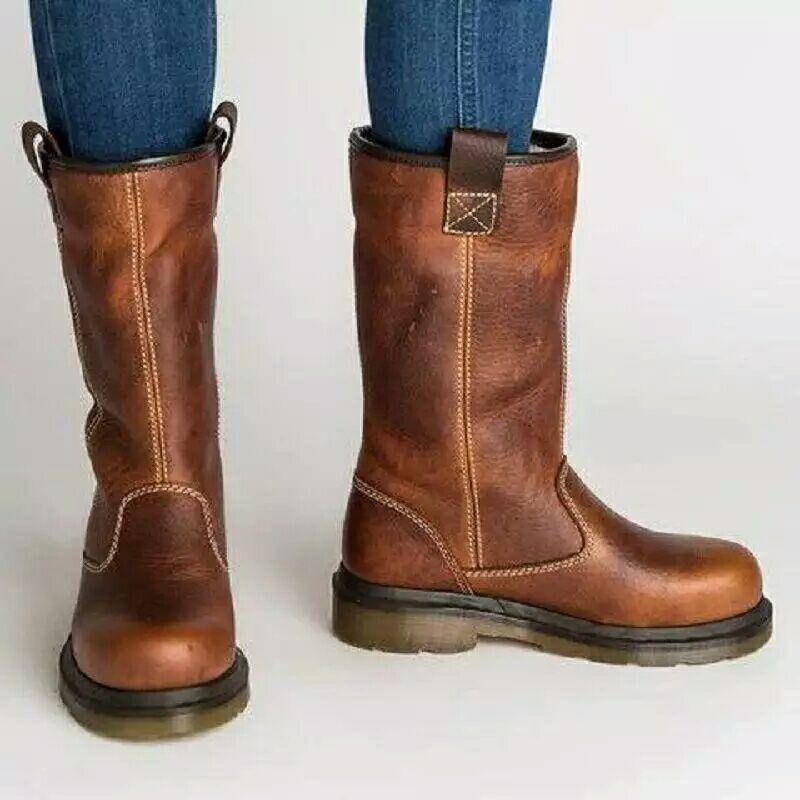 Brown leather boots worn with blue jeans on a white background