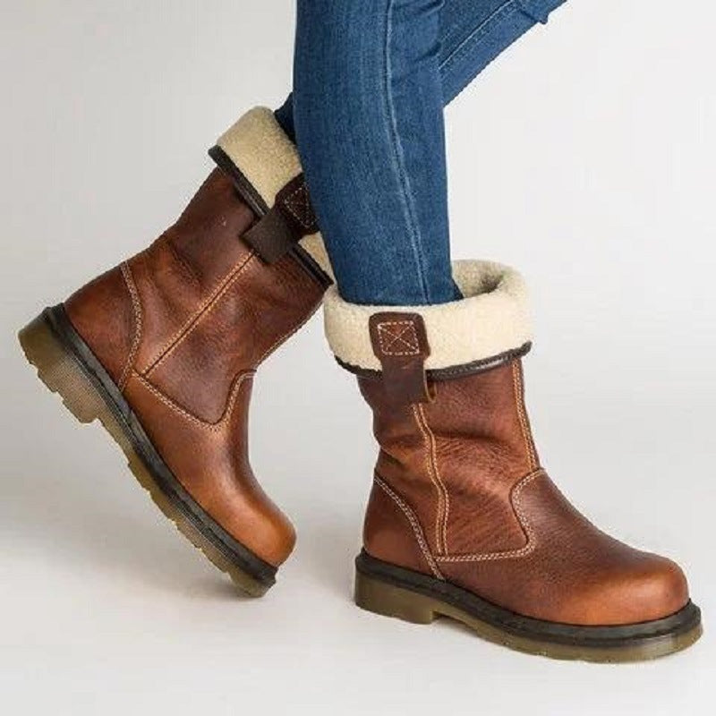 Brown winter boots with fur lining worn by a person on a light gray background