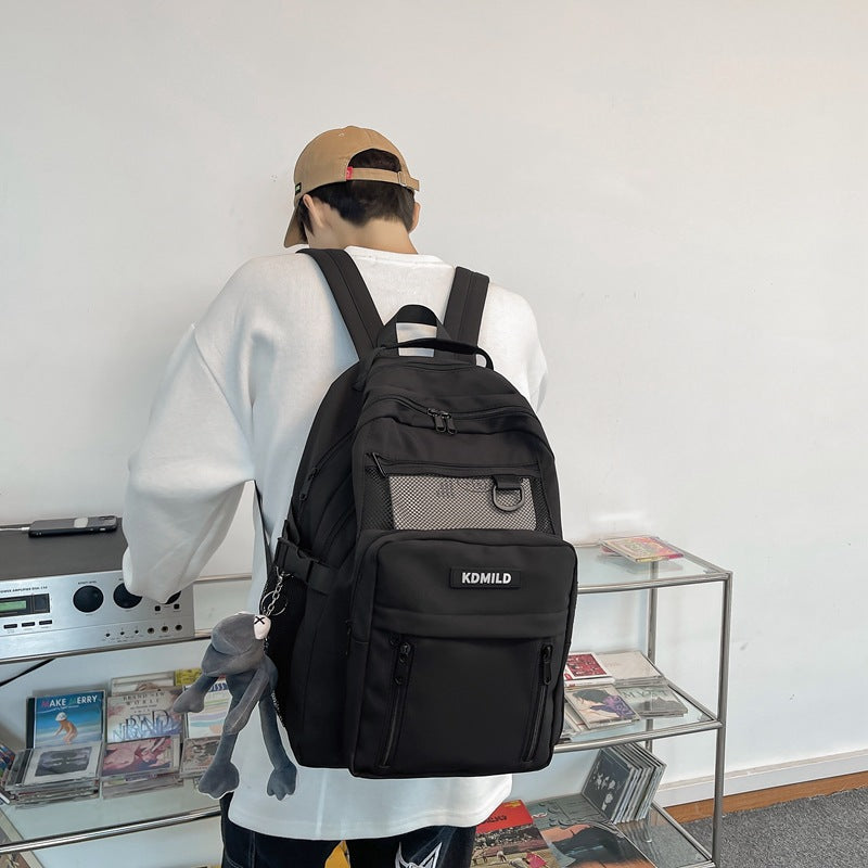 Person wearing a black backpack with 'KOMILD' branding in an indoor setting.