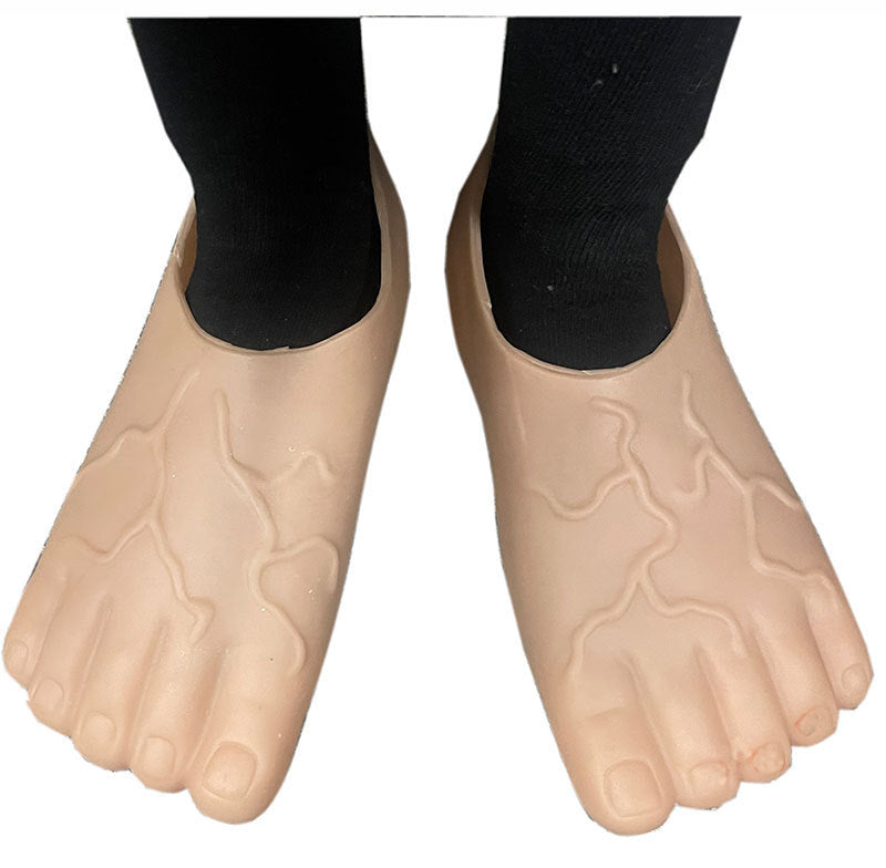 A pair of beige, foot-shaped silicone or rubber shoe covers with textured creases, shown on a person's feet wearing black socks against a white background.