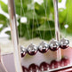 Newton's cradle with silver balls on a blurred green background