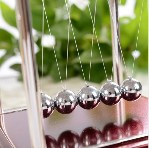 Newton's cradle with silver balls on a blurred green background