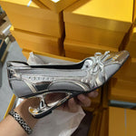 Silver high-heeled shoe held by a hand with yellow boxes in the background